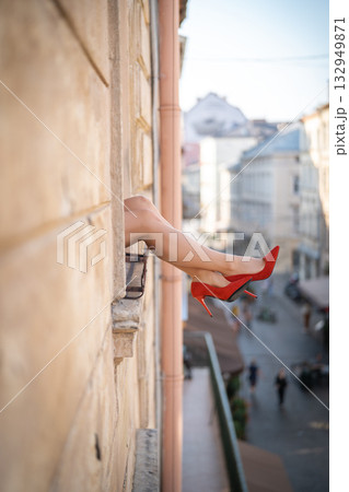Close-up of female legs with red shoes of high heels. The woman is raising her feet through the window 132949871