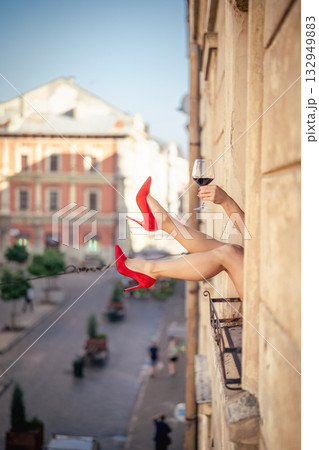 Close-up of female legs with red shoes of high heels. The woman is raising her feet through the window Close-up of female legs with red shoes of high heels. The woman is raising her feet through the window 132949883