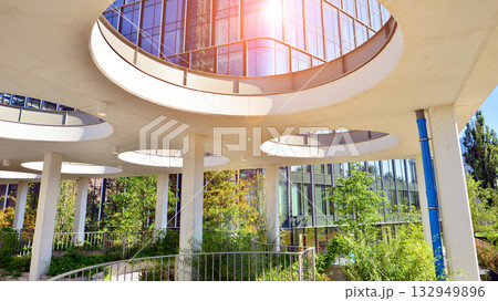 Modern luxury office building.The structure features a glass and concrete walls, showcasing contemporary architecture. The green surroundings of office buildings. Trees and shrubs in the city. 132949896