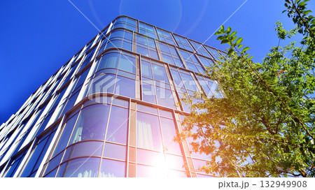Modern luxury office building.The structure features a glass and concrete walls, showcasing contemporary architecture. The green surroundings of office buildings. Trees and shrubs in the city. Modern luxury office building.The structure features a glass and concrete walls, showcasing contemporary architecture. The green surroundings of office buildings. Trees and shrubs in the city. 132949908