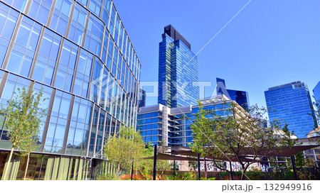 Modern luxury office building.The structure features a glass and concrete walls, showcasing contemporary architecture. The green surroundings of office buildings. Trees and shrubs in the city. Modern luxury office building.The structure features a glass and concrete walls, showcasing contemporary architecture. The green surroundings of office buildings. Trees and shrubs in the city. 132949916