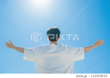 青空をバックに両手を広げる男性の後ろ姿 132950019