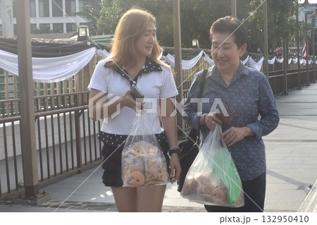 Asian elder woman and daughter enjoy talking after shopping with landscape view of Cho phraya river in Thailand on rainy day 132950410