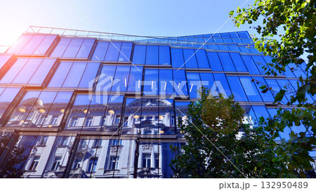Modern luxury office building.The structure features a glass and concrete walls, showcasing contemporary architecture. The green surroundings of office buildings. Trees and shrubs in the city. 132950489