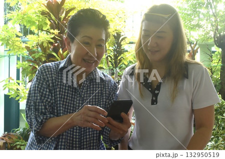 Asian elder woman and daughter to checking mobile phone in front of home 132950519