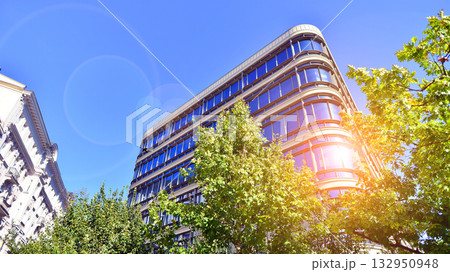 Modern luxury office building.The structure features a glass and concrete walls, showcasing contemporary architecture. The green surroundings of office buildings. Trees and shrubs in the city. Modern luxury office building.The structure features a glass and concrete walls, showcasing contemporary architecture. The green surroundings of office buildings. Trees and shrubs in the city. 132950948
