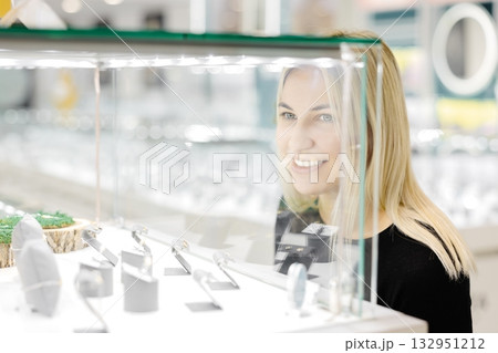 Woman looking on jewelry behind glass display in a store Woman looking on jewelry behind glass display in a store 132951212