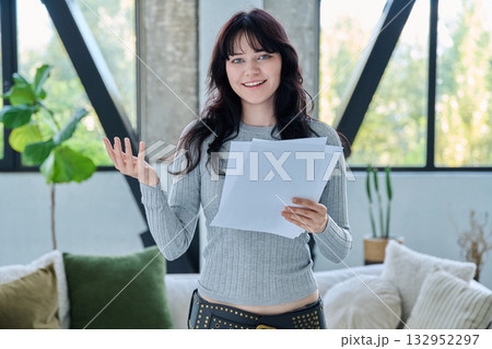Smiling young woman with business study important papers standing in home interior 132952297