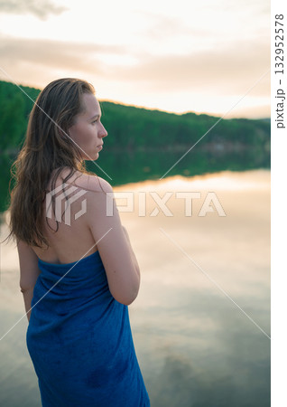 Woman Wrapped in Towel Relaxing by Lake at Sunset Woman Wrapped in Towel Relaxing by Lake at Sunset 132952578