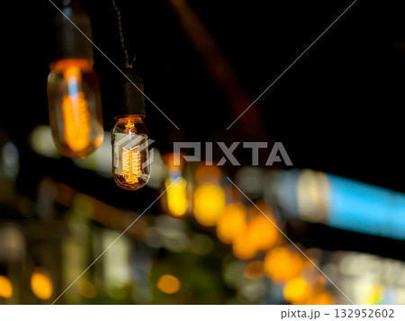 Warm Edison bulbs hanging string lights create cozy night scene for intimate gatherings 132952602