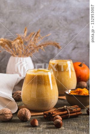 Warming pumpkin nut latte in glasses on the table vertical view 132953007
