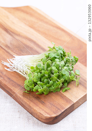 Mustard microgreens, bunch of fresh white mustard sprouts, on wooden cutting board, on linen. Seedlings and shoots of Sinapis alba, also yellow mustard, a spicy herb, used in salads, as garnish, etc. 132953060