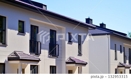 New single family houses in a new development area. Residential homes with modern facade. Terraced family homes in newly developed housing estate. The real estate market in the suburbs. New single family houses in a new development area. Residential homes with modern facade. Terraced family homes in newly developed housing estate. The real estate market in the suburbs. 132953315
