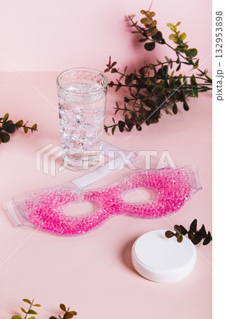 A trendy cryo skincare ice mask gadget on a pink table vertical view 132953898