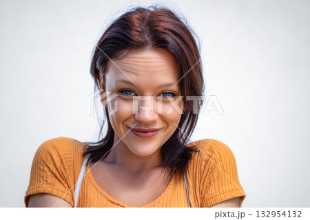Warm smile of a young woman with styled hair against a light background in a casual setting Warm smile of a young woman with styled hair against a light background in a casual setting 132954132