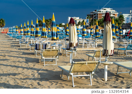 Sun loungers on sandy beach with Umbrellas. Empty seaside resort. Italy. Sun loungers on sandy beach with Umbrellas. Empty seaside resort. Italy. 132954354
