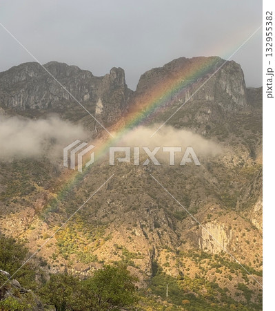 Beautiful rainbow stretching over mountain peaks in Montenegro, scenic natural landscape with cloudy sky and sunlight 132955382