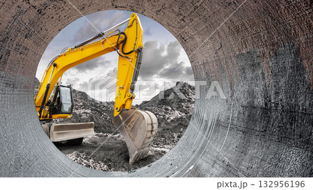 A vibrant yellow excavator works diligently at a construction site, digging into the earth while framed by a cylindrical pipe 132956196