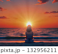 Woman meditating at sunset beach A woman sitting calmly on the beach facing the ocean as the sun sets, symbolizing tranquility, mindfulness, and inner harmony. 132956211
