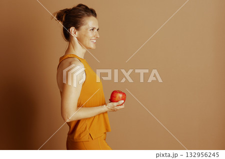 Woman in Orange Activewear with Apple 132956245