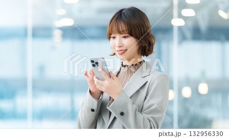 スマートフォンを使う笑顔の女性・ビジネスウーマン 132956330