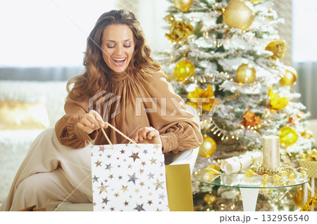 Joyful Woman Opening a Star-Patterned Gift Bag Joyful Woman Opening a Star-Patterned Gift Bag 132956540