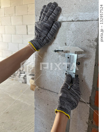 A construction worker uses a caliper to measure the diameter of a screw. A construction worker uses a caliper to measure the diameter of a screw. 132957524