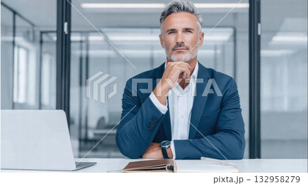 man is seated at a white desk in a modern office 132958279
