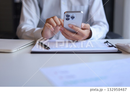 Businessman working in office using smartphone. Businessman working in office using smartphone. 132958487