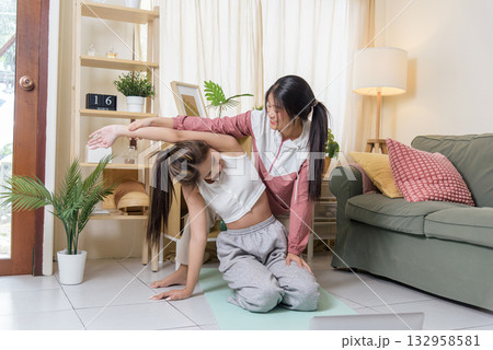 Young women workout yoga active teen teaching friend exercising sport, showing proper form for side bend stretch, enjoying active lifestyle for better health and wellness indoors. Young women workout yoga active teen teaching friend exercising sport, showing proper form for side bend stretch, enjoying active lifestyle for better health and wellness indoors. 132958581