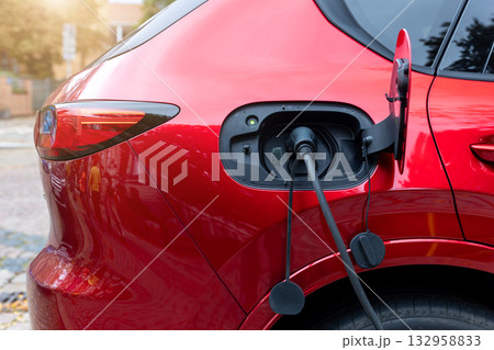 Close-up modern electric plug-in hybrid car SUV van parked   fast charger charging station point center street old European city. Eco friendly green energy vehicle. Zero emission transport technology 132958833