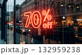 Neon sign advertising a 70% off sale in a shop window at dusk 132959238