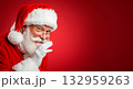 Santa Claus winks and gestures a secret on a vibrant red background 132959263