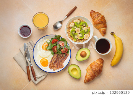 Breakfast warm beige background eggs vegetables salad, oats fruit, croissants, coffee, juice healthy morning. Breakfast warm beige background eggs vegetables salad, oats fruit, croissants, coffee, juice healthy morning. 132960129