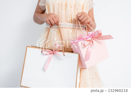 Caucasian young female in elegant dress holding pink and white gift bags with ribbons 132960218