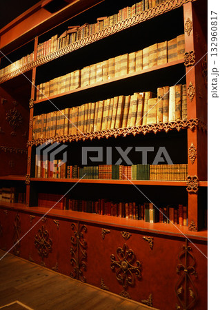 An atmospheric vintage library with carved wooden bookshelves and rows of antique books in Porto, Portugal. A concept for lovers of literature, fantasy, and dark, academic interiors. 132960817