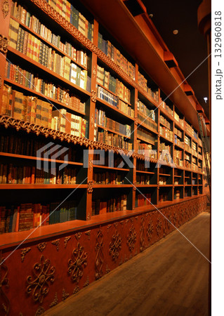 An atmospheric vintage library with carved wooden bookshelves and rows of antique books in Porto, Portugal. A concept for lovers of literature, fantasy, and dark, academic interiors. 132960818