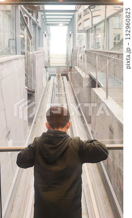 A toddler boy looks at the elevator mechanism in a transparent cable car. Concept of modern technology, child development 132960825
