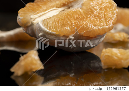 half of an orange citrus on a mirror surface, ripe sweet and juicy citrus is reflected on the black surface 132961377
