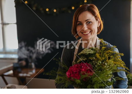 Smiling female florist working in her small flower shop. 132962060