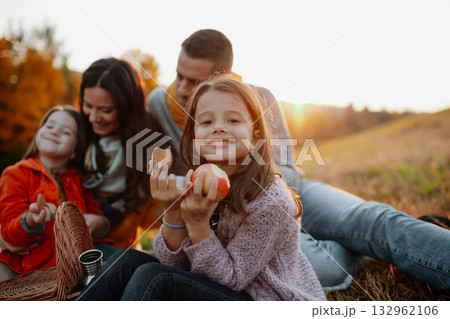 Parents with young children sitting outdoors in autumn light. 132962106