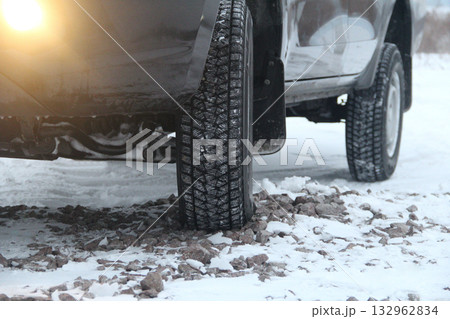 Car wheel with winter tire on the gravel road at winter time 132962834