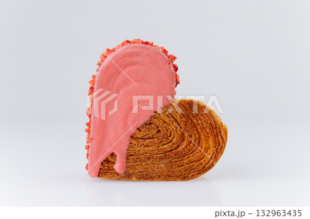Heart-shaped croissant with pink icing and crushed strawberry topping on white background Heart-shaped croissant with pink icing and crushed strawberry topping on white background 132963435