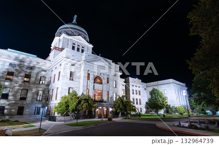 The Montana State Capitol in Helena is illuminated at night. The bright lights highlight the stone facade, columns, and dome, contrasting with the dark sky The Montana State Capitol in Helena is illuminated at night. The bright lights highlight the stone facade, columns, and dome, contrasting with the dark sky 132964739