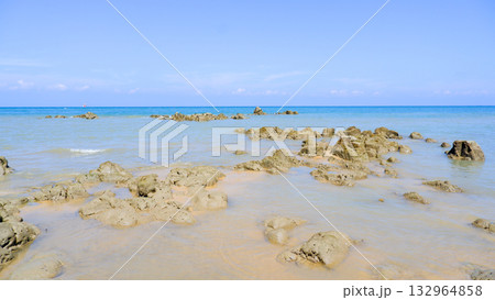 Rocky Shoreline and Clear Blue Ocean Water Under a Vivid Summer Sky at Low Tide Rocky Shoreline and Clear Blue Ocean Water Under a Vivid Summer Sky at Low Tide 132964858