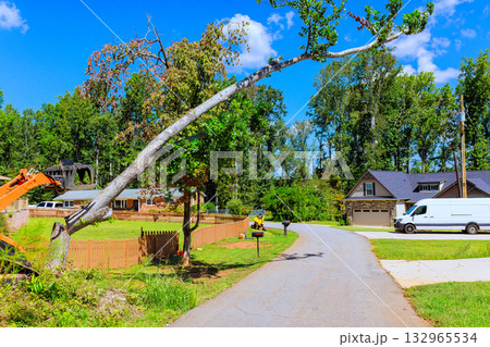 Workers are removing large, leaning tree in quiet neighborhood under works day Workers are removing large, leaning tree in quiet neighborhood under works day 132965534