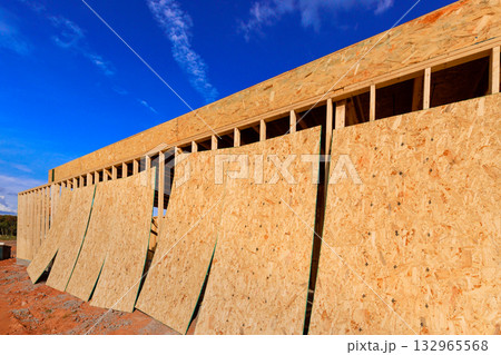 Workers are preparing wooden structure of building with sheets of plywood board placed on exterior facing 132965568