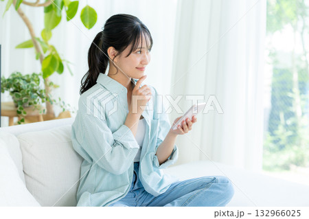 部屋でスマホを操作する若い女性 132966025