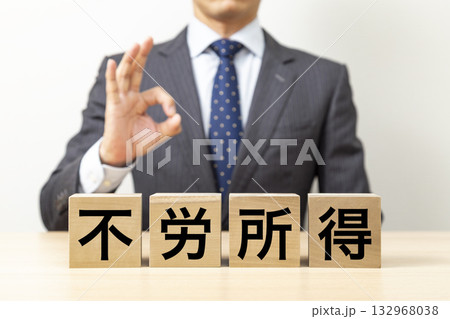 「不労所得」と書かれたブロックとOKポーズをするビジネスマン 132968038