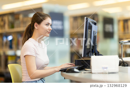 Young female student working on computer in library Young female student working on computer in library 132968129